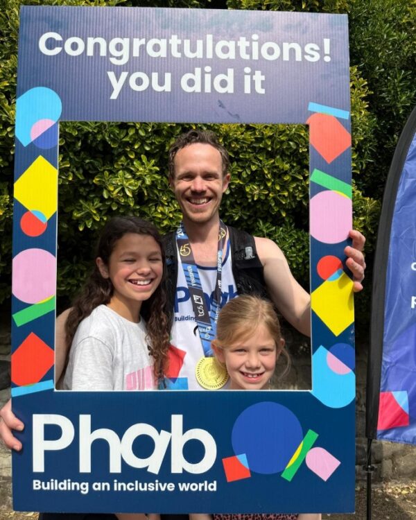 Two children and an adult are standing holding a large frame using "Congratulations! you did it"