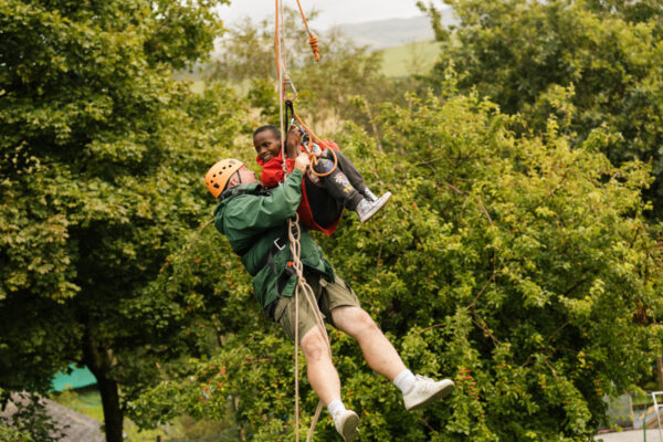A man and a child on a zip line, smiling and happy
