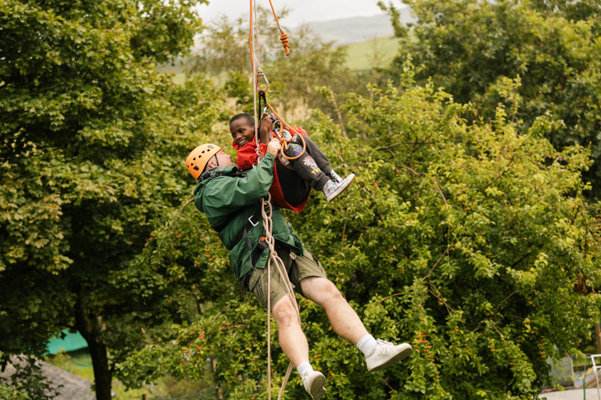 A man and a child on a zip line, smiling and happy